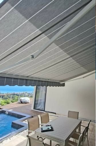 Store banne gris rayé au-dessus d'une terrasse et d'une piscine